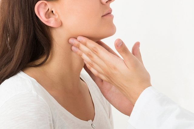 A doctors hands touching and examining a woman's neck front.