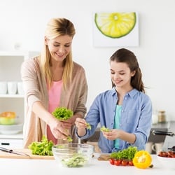 Supports the Gut – Mother and teenage daughter preparing a salad in the kitchen