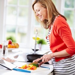 Promotes Normal Blood Sugar – Woman following recipe and cutting vegetables in the kitchen