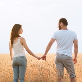 Heightened Sexual Response – Couple standing in a field holding hands and lovingly looking at each other