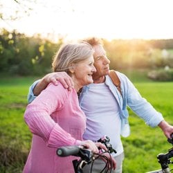 Seasonal Wellness – Middle-aged couple riding bicycles in the park