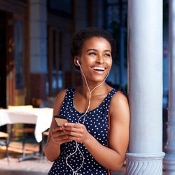 Bye-Bye Harmful Organisms – Woman smiling and listening to music while leaning against an outdoor pole  