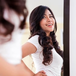 Fasting & Weight Loss – Woman smiling in front of a mirror.