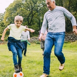 Supports Bone Health – Father and son playing soccer in the backyard