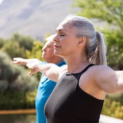 Promotes Heart Health – Man and woman practicing yoga outdoors