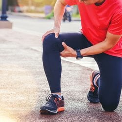Quickens Healing – Man stretching his leg on a sidewalk