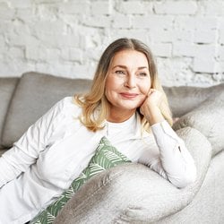 Makes Skin Glow – Woman smiling while lounging on the couch